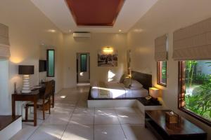 a bedroom with a bed and a table and a desk at The Chandi Boutique Resort & Spa in Senggigi