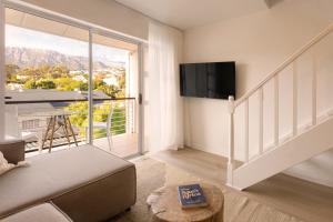 a living room with a large window and a tv at Four Peaks Duplex - 4 Sleeper with Mountain Views, Balcony and Pool in Hout Bay Beachfront in Hout Bay