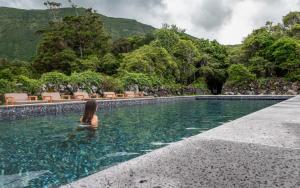 a woman sitting in the water in a swimming pool at Aldeia da Cuada in Faja Grande