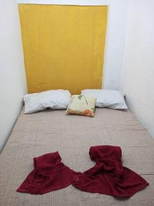 a bed with two pillows and red sheets on it at Casa Amarela, Ilha dos Frades in Salvador