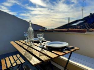 a wooden table with a bottle and glasses on a balcony at Appartement avec terrasse tropezienne, Aups in Aups +4 photos