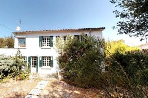 une maison blanche avec des fenêtres à volets verts dans l'établissement Villa Saint Trojan, à Saint-Trojan-les-Bains