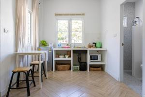a kitchen with a table and some stools in a room at Vawa Guesthouse in Kanchanaburi City