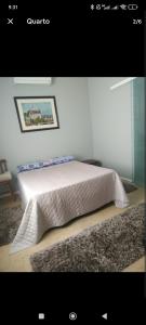 Un dormitorio con una cama blanca y un cuadro en la pared. en Casa Urbana, en Blumenau