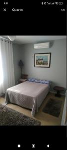 1 dormitorio con 1 cama con colcha blanca y mesa en Casa Urbana, en Blumenau