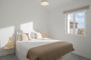 a white bedroom with a large bed with a window at Casa Areia Dourada by An Island Apart in Porto Santo