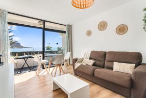 a living room with a couch and a table at Home2Book Cosy Studio Pool Sea Views Mogán in Mogán