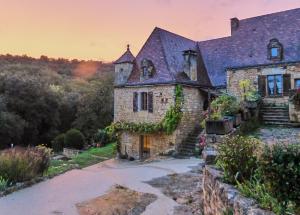 an old stone house with ivy on it at Domaine de Cantegrel - Gîtes de Charme et Suite Troglodyte en Périgord in Vitrac