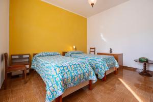 a bedroom with two beds and a yellow wall at Appartamento Casa Rita - Sorano in San Giovanni delle Contee