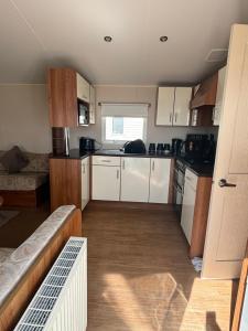 a small kitchen with white cabinets and a couch at Beautiful , spacious two bedroom caravan home in Eastchurch +7 photos