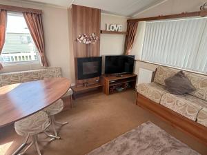 a living room with a table and a television at Beautiful , spacious two bedroom caravan home in Eastchurch