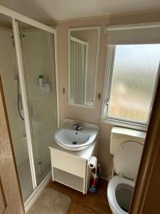 a small bathroom with a toilet and a sink at Beautiful , spacious two bedroom caravan home in Eastchurch