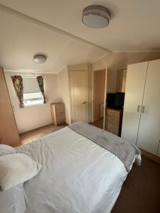a bedroom with a large white bed and a kitchen at Beautiful , spacious two bedroom caravan home in Eastchurch