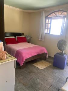 a bedroom with a bed with red pillows and a window at Refugio da Marvila in Marataizes