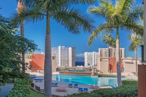 a swimming pool with palm trees and buildings at Paradise Beach Bay in Adeje