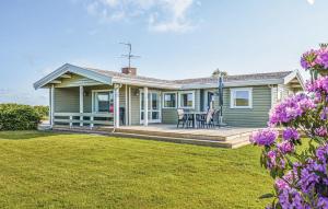 ein grünes Haus mit einer Terrasse mit 2 Stühlen in der Unterkunft Holiday Home Skonnertvej Ebeltoft Xii in Ebeltoft