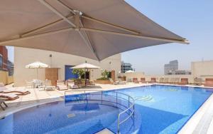 a large swimming pool with a large umbrella and chairs at Havana Holiday Homes Oud Metha in Dubai