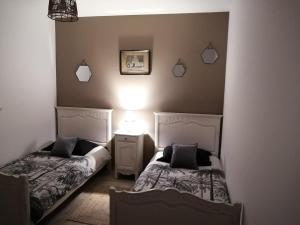 a bedroom with two beds and a lamp on the wall at La Régate du Plaisir- Jacuzzi privé, Plage à 900m in Houlgate