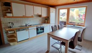 a kitchen with white cabinets and a table with chairs at Ferienwohnung Iris in Tschagguns