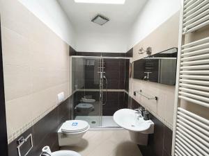 un bagno con due WC, una doccia e un lavandino di InCorteDaFabio Design flat with Bikes a Caronno Pertusella Altre 7 foto
