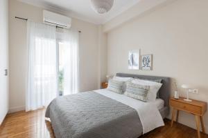 a white bedroom with a bed and a window at Home of Petros in Athens