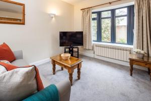 ein Wohnzimmer mit einer Couch, einem Fernseher und einem Tisch in der Unterkunft The Uplands Apartments in Saint Helier Jersey