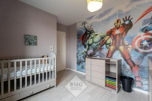 una guardería con un mural de superhéroes en la pared en Villa Debussy Disneyland, en Bussy-Saint-Georges