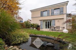 una casa con un cartel frente a un estanque en Villa Debussy Disneyland, en Bussy-Saint-Georges