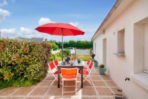 a table with a red umbrella on a patio at 1er étage, jardin partagé pour 4 à 300m de la plage in Le Guilvinec