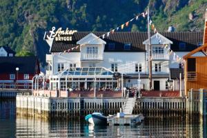 a boat is docked next to a building on the water at Anker Brygge in Svolvær