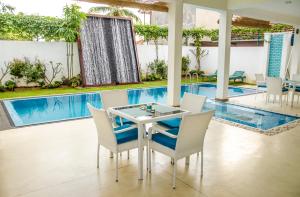 a dining room with a table and chairs next to a swimming pool at Binnacle Negombo in Negombo