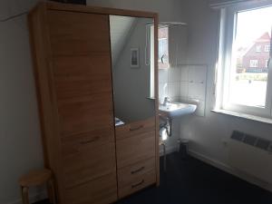 a bathroom with a tall wooden cabinet and a sink at Deichblick Süderloog 38 in Spiekeroog