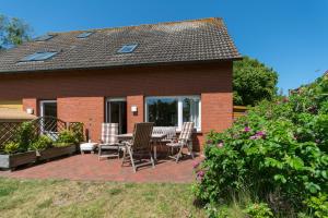 a patio with chairs and a table in front of a house at Deichblick Süderloog 38 in Spiekeroog