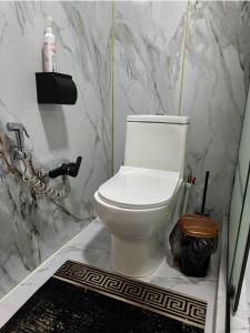 a white toilet in a bathroom with marble walls at Стильные апартаменты ближе караван сарая in Türkistan +13 photos