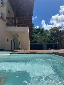 a swimming pool in front of a house at Su House Suíte Arraial dAjuda in Porto Seguro