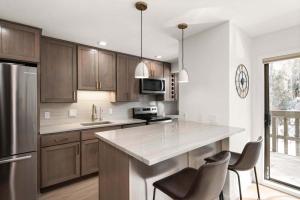 una cucina con armadi in legno e bancone con sedie di Renovated Riverfront 3 BR, 2 BA with Pool - Walk to Town! ad Aspen Altre 78 foto
