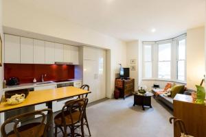 a kitchen and living room with a table and a couch at Stunning One Bedroom Apartment in Fitzroy in Melbourne