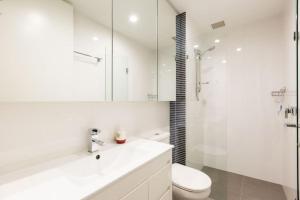 a white bathroom with a toilet and a sink at Stunning One Bedroom Apartment in Fitzroy in Melbourne +5 photos