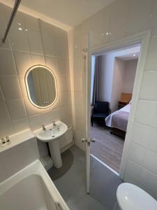 a bathroom with a sink and a toilet and a tub at Westlynn Hotel & Apartments Free Parking Near Manchester Centre in Manchester +28 photos