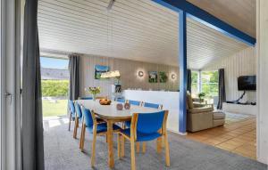 a dining room with a table and blue chairs at Holiday Home Pøt Strandby Denm in Sønderby