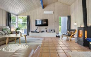 a living room with a couch and a tv at Holiday Home Pøt Strandby Denm in Sønderby