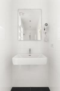 a white bathroom with a sink and a mirror at Bed & Bike De Dorsvloer in Domburg +31 photos