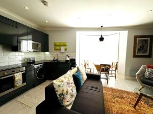 a living room with a couch and a kitchen at Waves, Central Beach Town Apartment in Hastings