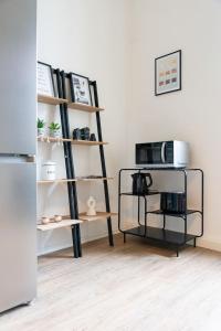 a kitchen with a shelf with a microwave and a refrigerator at Goodliving Apartments Magdeburg in Magdeburg +7 photos