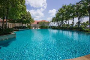 une grande piscine bleue avec des arbres en arrière-plan dans l'établissement WHITE HOUSE STRAITS QUAY MARINA LUXURY STAY GURNEY, à Tanjong Tokong