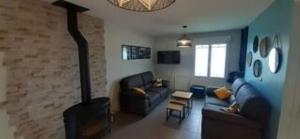 Una sala de estar con un sofá y una chimenea. en Hébergement Plage du Débarquement, en Foucarville