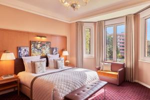 a bedroom with a bed and a chair and windows at Hôtel Barrière Le Westminster in Le Touquet-Paris-Plage +37 photos