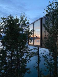 a glass house with a tree reflection in the water at Yttervik in Mo i Rana