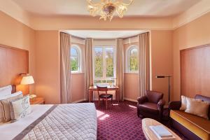 a hotel room with a bed and a chair and windows at Hôtel Barrière Le Westminster in Le Touquet-Paris-Plage