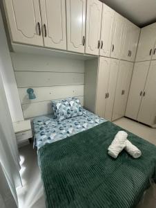 a room with a bed with a green blanket and white cabinets at Apartamento 01suite e um quarto in Balneário Camboriú